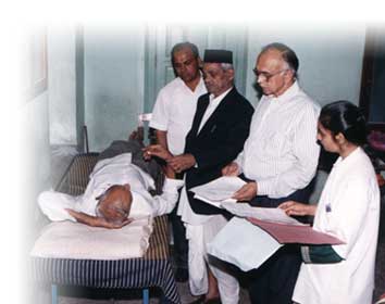 Sardeshmukh Maharaj checking patients along with Dr. S. P. Sardeshmukh and Dr. Arvind Kulkarni